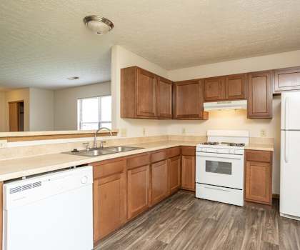 A kitchen with white appliances and wooden cabinets.
