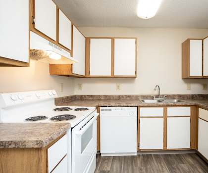 A kitchen with white appliances and wooden cabinets.
