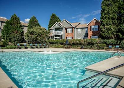 A swimming pool in front of a building with trees around it.