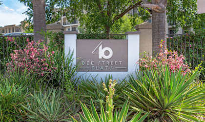 a sign in front of a building with trees and plants