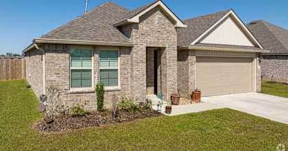 a brick house with a brown roof and a driveway