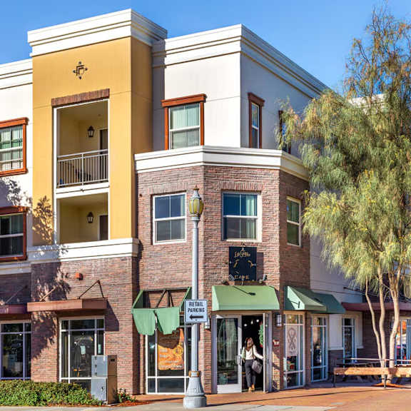 A street view of a shopping area with a yellow building on the left.