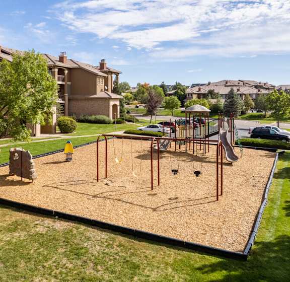 a playground in the middle of a park with houses in the background