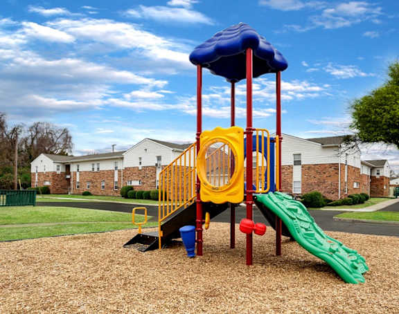 A playground with a yellow slide and a blue canopy.