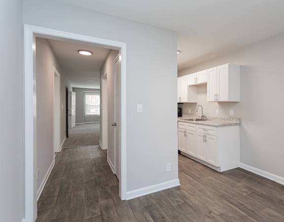 a renovated kitchen with white cabinets and a wood floor