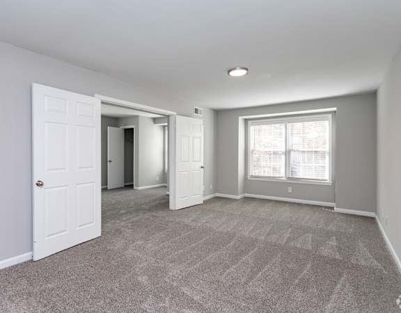 an empty room with white doors and a window