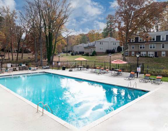 a pool with chairs and umbrellas next to a building