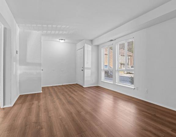 a living room with white walls and wood floors and a window