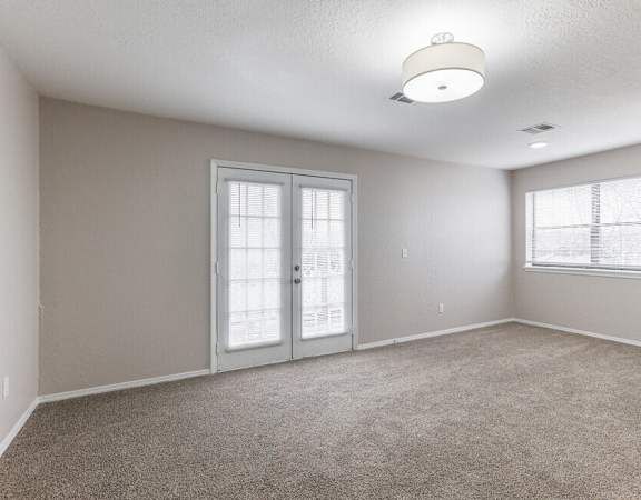 an empty living room with a white door and window