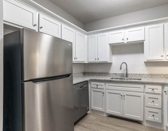 a kitchen with white cabinets and a stainless steel refrigerator