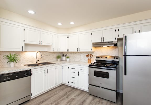 A modern kitchen with white cabinets and stainless steel appliances.