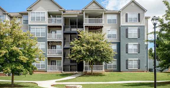 A large apartment complex with multiple balconies and trees in front.