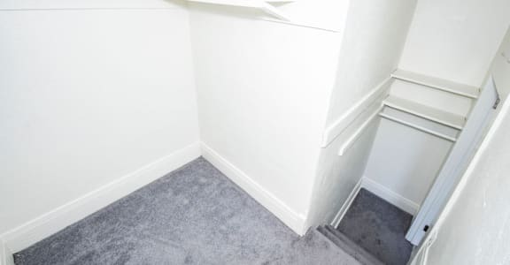 A small, empty room with a carpeted floor and a stairway leading to another level.
