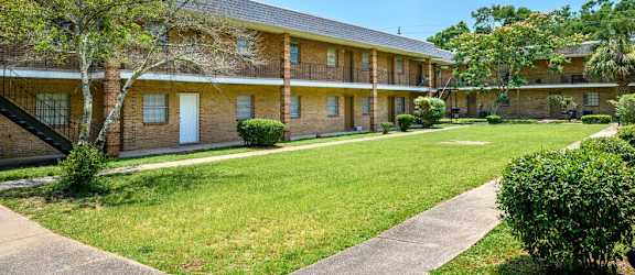exterior view of a brick building with a lawn and sidewalk