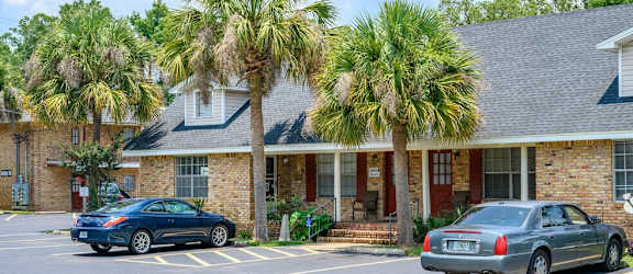 the front of a brick building with palm trees and cars parked in front