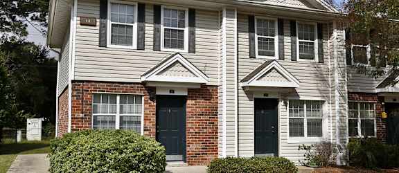 a white house with two black doors and a sidewalk