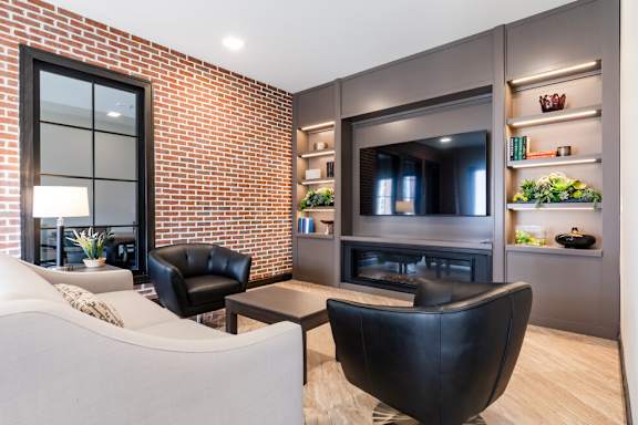 A modern living room with a brick wall and a fireplace.