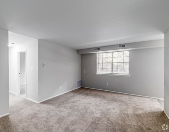 the living room of a new home with carpet and a window