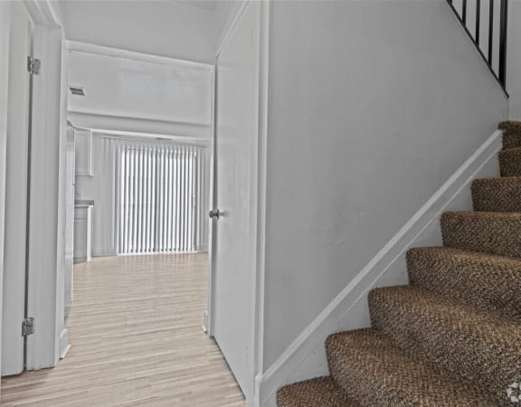 the landing of a staircase leading to a hallway with a door to a living room
