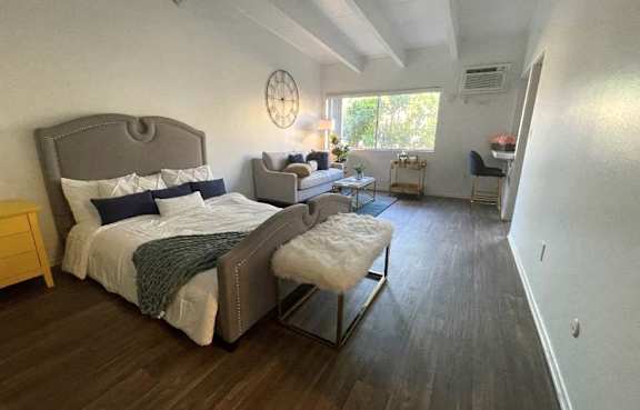 A bedroom with a large bed and a chair at The Marquee Apartments, North Hollywood, California