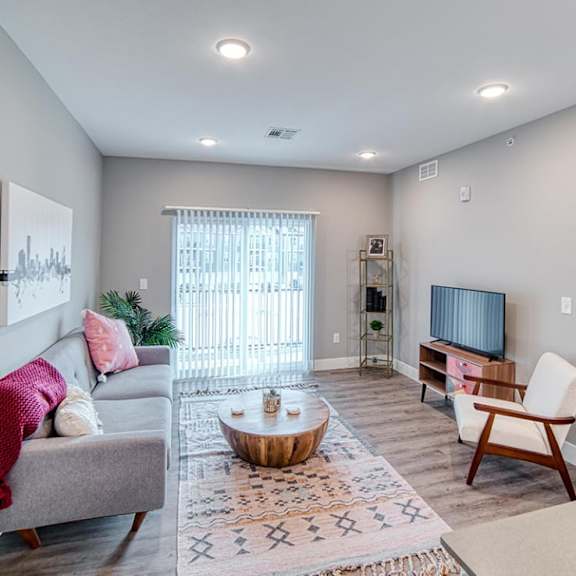 an open concept living room and dining area with a white dining table and rattan chairs at Westown at Wilson, Grand Rapids