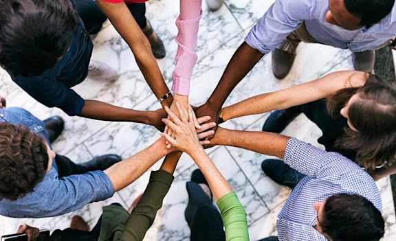 a group of people putting their hands together in a circle