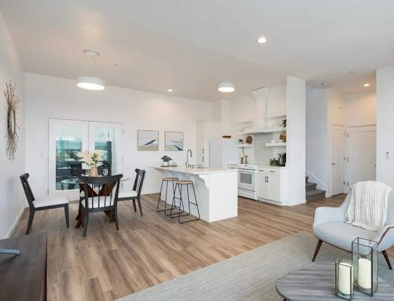 A modern kitchen and dining area with wooden floors and white walls.