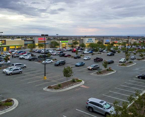A parking lot with cars and a few trees.