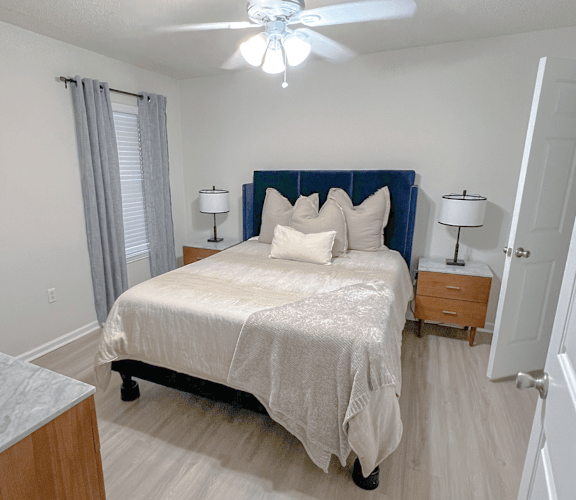 A bedroom with a bed, nightstands, and a ceiling fan.