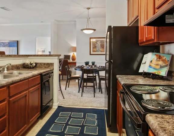 an empty kitchen with white cabinets and black appliances at Uphill Flats, Georgia, 30032
