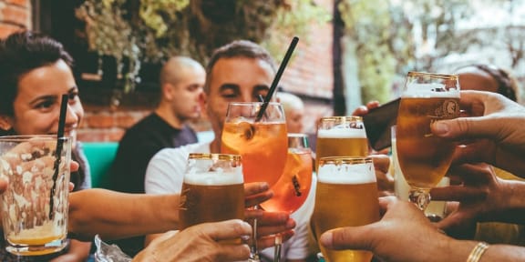 a group of people sitting around a table drinking beer