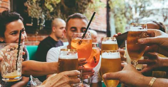 a group of people sitting around a table drinking beer