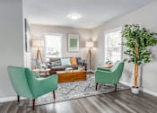Thumbnail 1 of 13 - A living room with a green chair and a wooden coffee table.