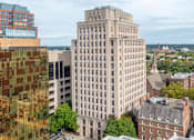 Thumbnail 1 of 74 - A large building with many windows sits in the middle of a city.