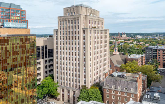 A large building with many windows sits in the middle of a city.