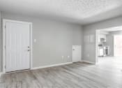 Thumbnail 5 of 13 - A white door is on the left side of a room with a wooden floor.