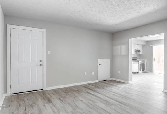 A white door is on the left side of a room with a wooden floor.