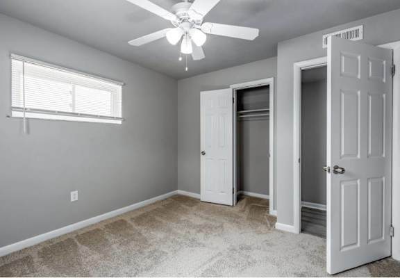 A room with a ceiling fan and three doors.
