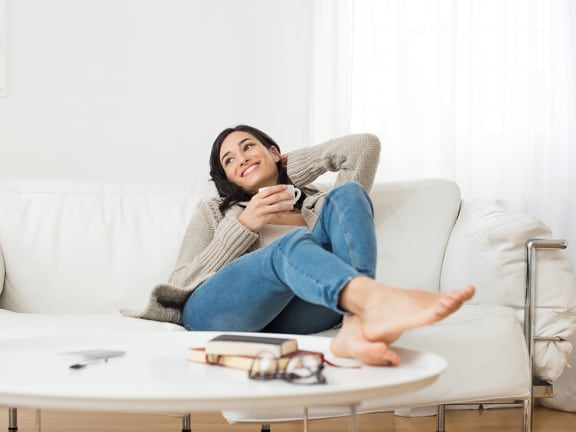 a woman sitting on a couch holding a cell phone at The Georgian Apartments, St Louis, MO, 63104