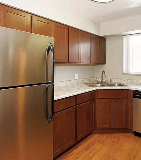 A kitchen with a stainless steel refrigerator and wooden cabinets.