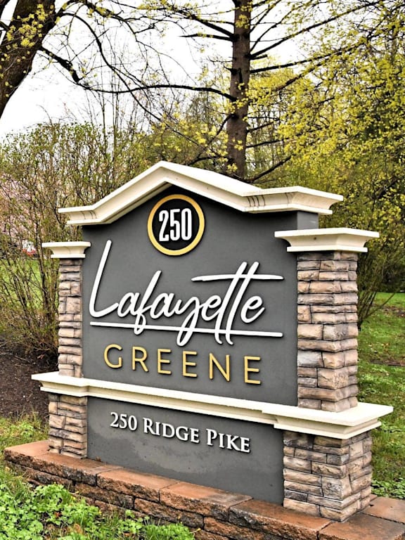 A sign for Lafazette Greene stands in front of a tree.