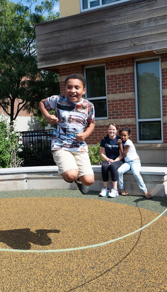 a boy jumping in the air in front of a house
