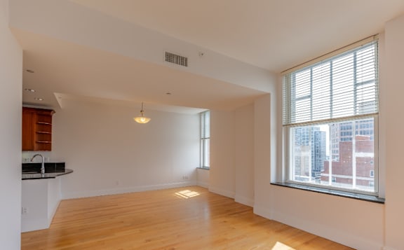 A large empty room with wooden floors and a window overlooking a cityscape.