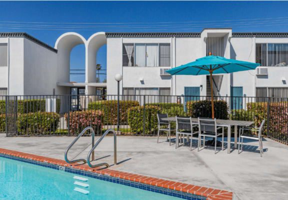 our apartments have a swimming pool and a patio with a table and umbrellaat The Arches Apartments, LLC, El Cajon California