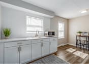 Thumbnail 3 of 13 - A kitchen with white cabinets and a microwave on the counter.