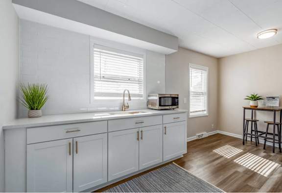 A kitchen with white cabinets and a microwave on the counter.