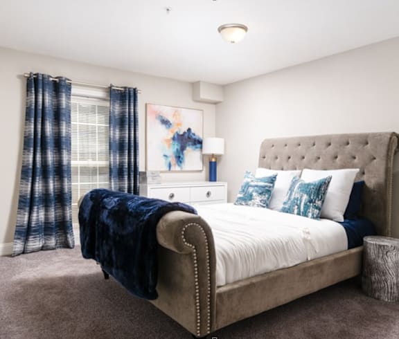 a bedroom with a bed and a window with blue and white curtains