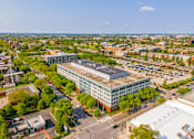 Thumbnail 56 of 59 - A large building with a glass facade is surrounded by trees and other buildings.