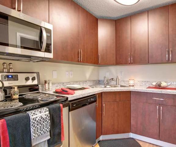 A kitchen with a microwave, oven, sink and wooden cabinets at 3600 Brentwood.