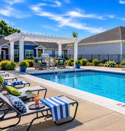 A pool with chairs and a house in the background.